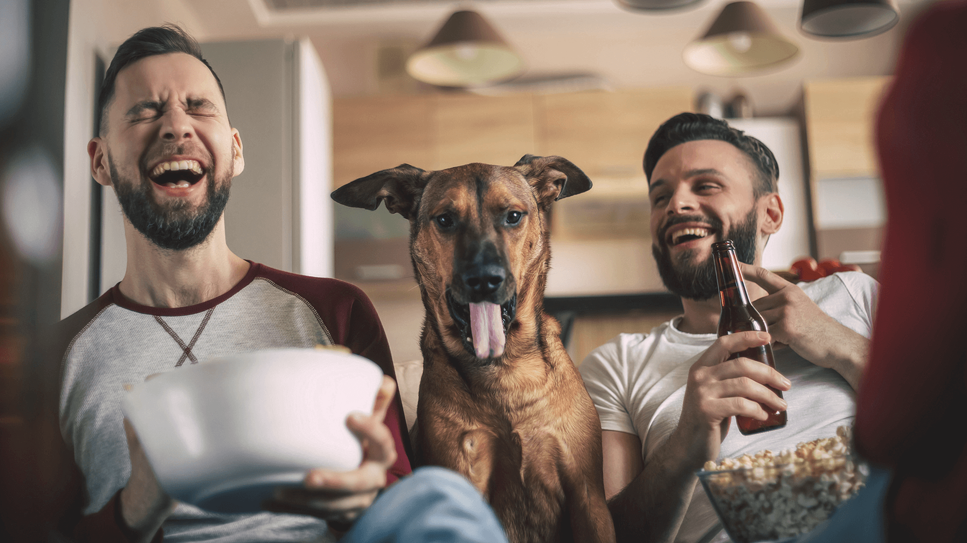 two men smiling with a dog in between them